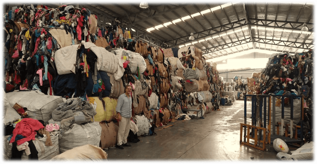 Man stands in full warehouse of used credential clothing