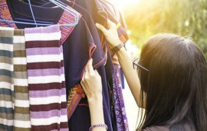 Woman inspects vintage clothing at thrift store