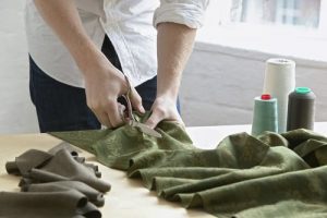 A man cutting cloth for clothing