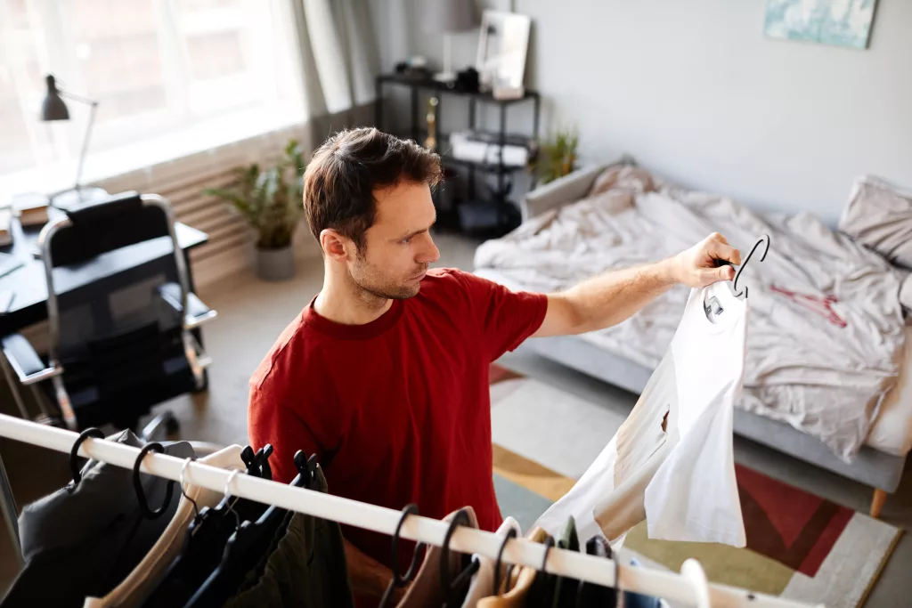 A man choosing a shirt to wear from his closet